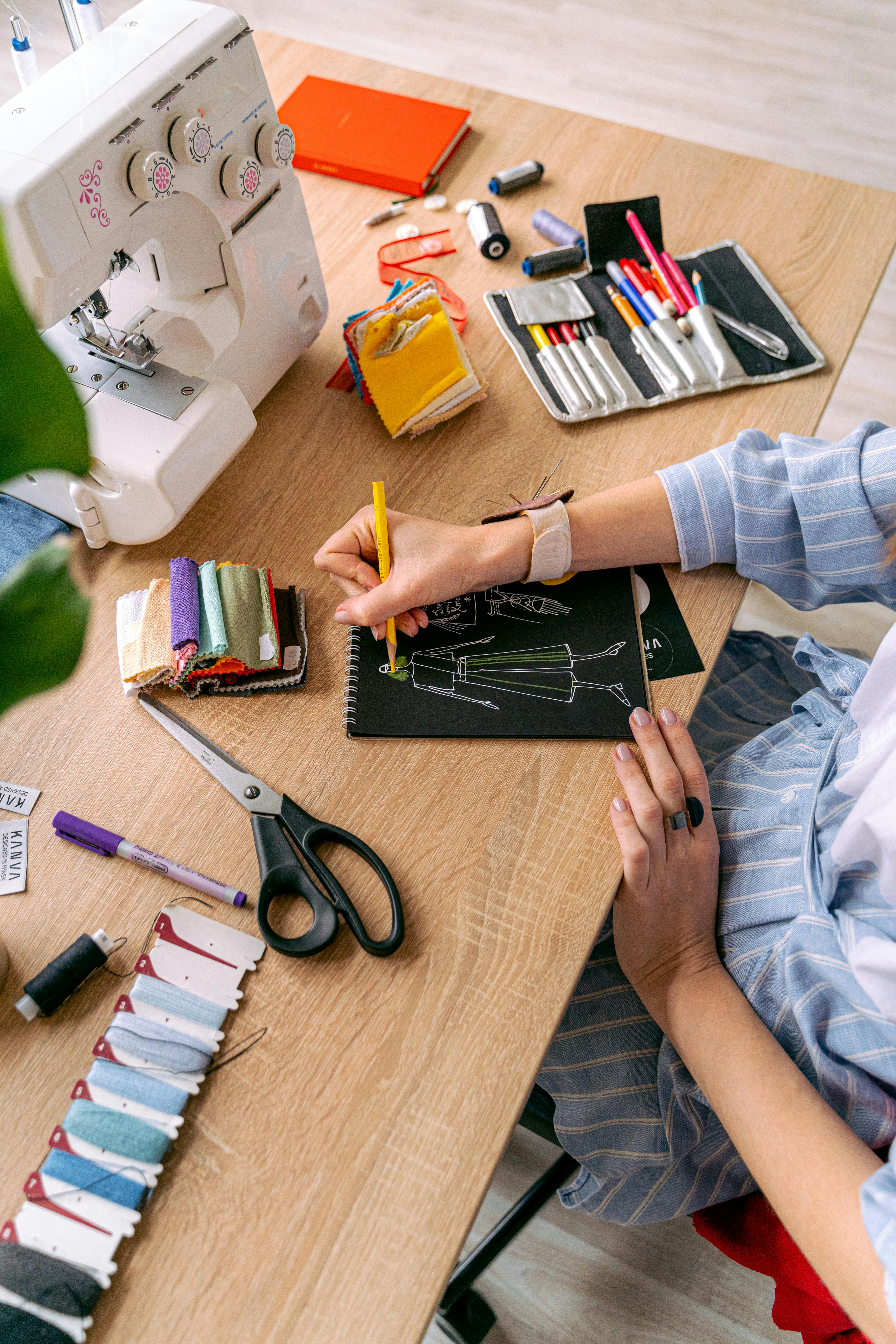 Person at sewing desk drafting a fashion illustration. 